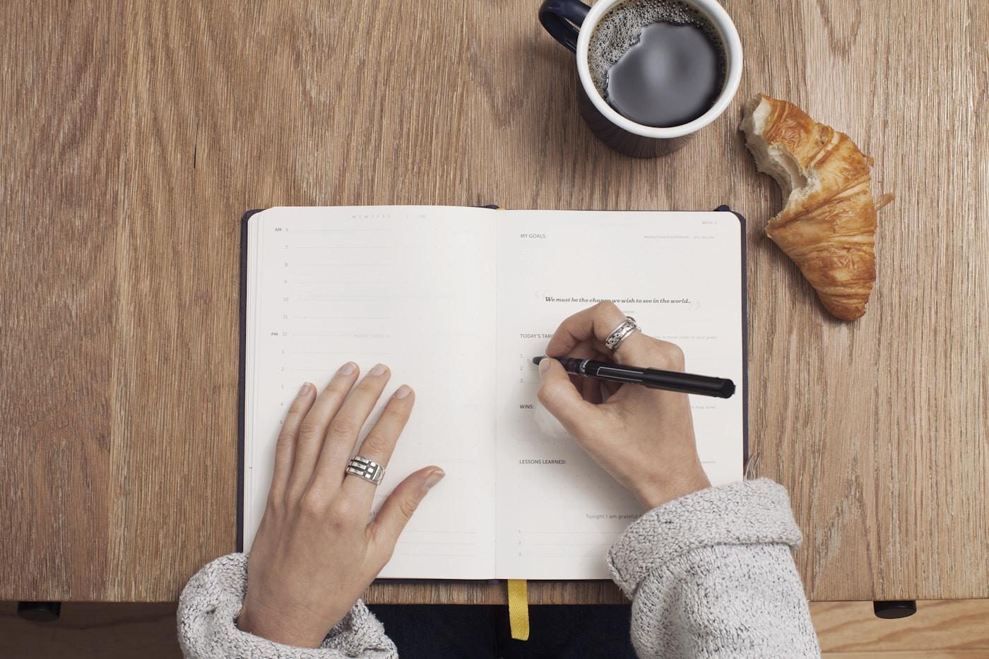 Hands writing and reviewing notes in an open notebook.
